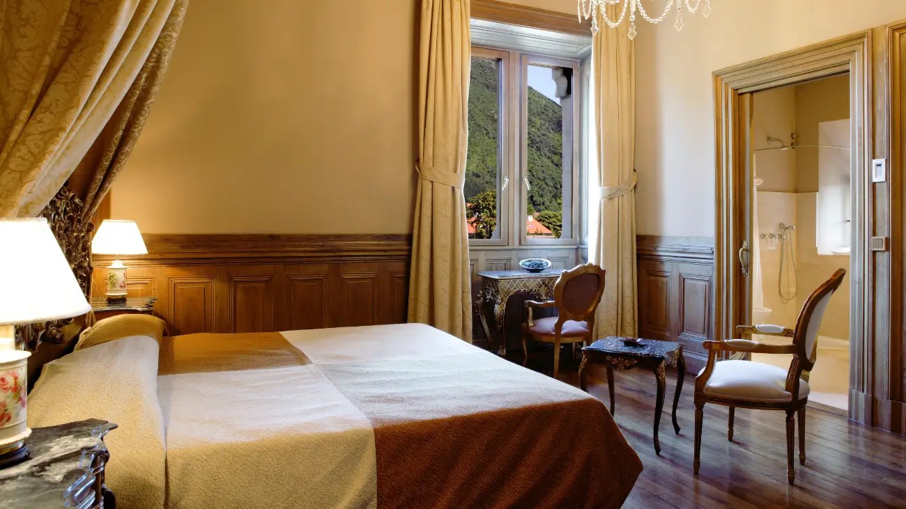 Fotografía de una habitación amplia y elegante de estilo clásico. La estancia cuenta con una cama doble vestida con ropa de cama en tonos claros y ...