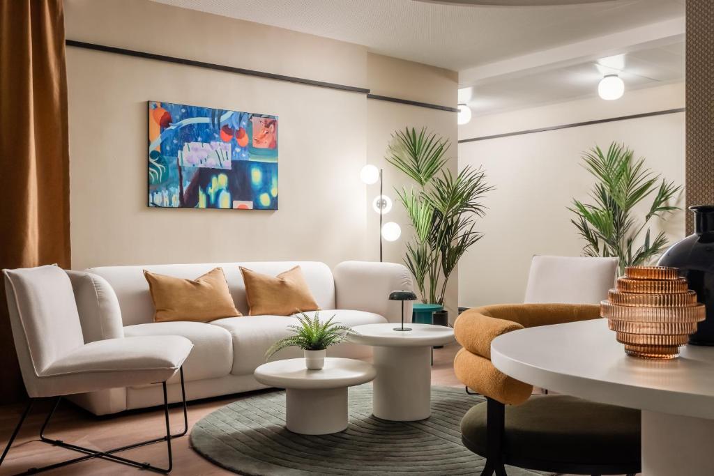 Photographie d’un salon lumineux au design moderne, comprenant un canapé blanc aux formes courbes avec des coussins couleur moutarde, installé sur ...