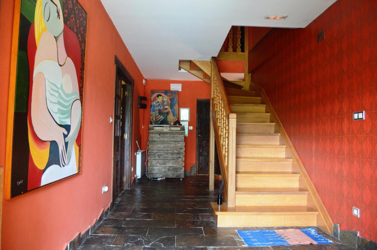 L’image montre un couloir intérieur de style rustique avec des murs couleur terracotta et un sol en carreaux irréguliers foncés. Sur le côté ...