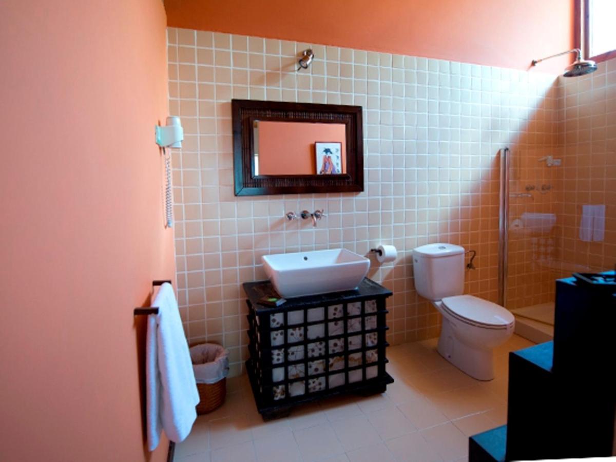 L’image montre une salle de bains de style rustique et chaleureux avec des murs couleur pêche et une zone centrale recouverte de carreaux carrés ...