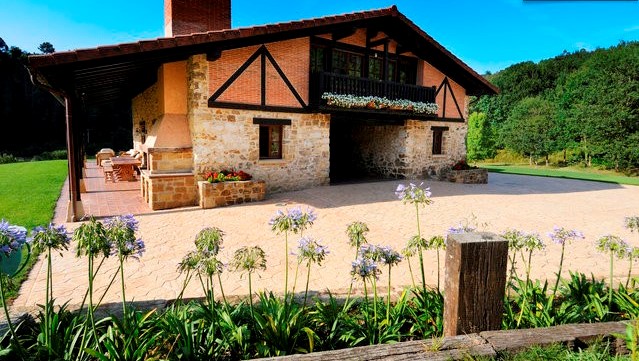This photograph shows the exterior of a country house with stone walls on the lower floor and a brick upper section with dark wooden framework. ...